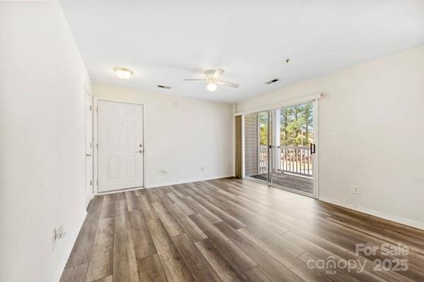 unfurnished room with ceiling fan, wood finished floors, visible vents, and baseboards