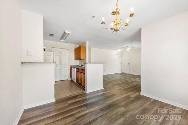 kitchen featuring brown cabinetry, dark wood-type flooring, dishwasher, and a peninsula