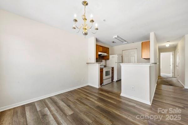 kitchen featuring white appliances, brown cabinetry, dark wood finished floors, light countertops, and under cabinet range hood