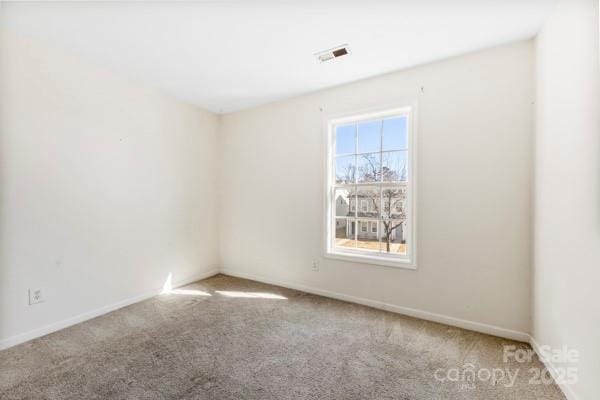 spare room featuring light carpet, visible vents, and baseboards