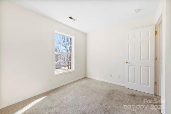 empty room featuring light carpet, visible vents, and baseboards