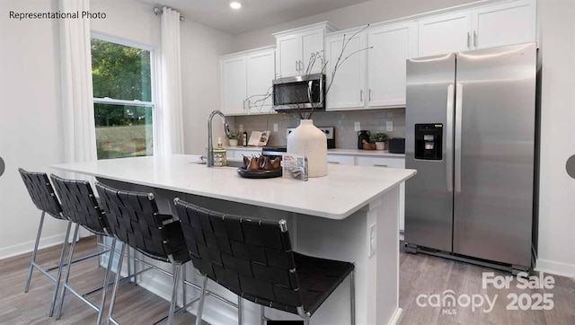 kitchen featuring light countertops, appliances with stainless steel finishes, white cabinets, and a kitchen breakfast bar