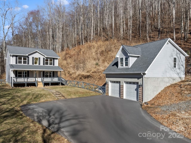 view of front of property with roof with shingles, a porch, a garage, driveway, and a front lawn