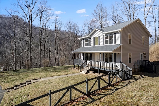 colonial inspired home with covered porch, fence, roof with shingles, stairway, and a front lawn