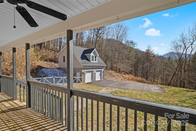 deck with a garage, ceiling fan, and a yard