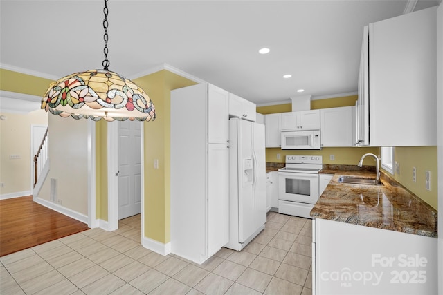 kitchen with white appliances, ornamental molding, white cabinetry, pendant lighting, and a sink