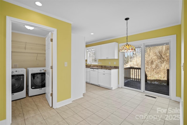 kitchen featuring visible vents, dishwasher, dark countertops, hanging light fixtures, and washing machine and dryer