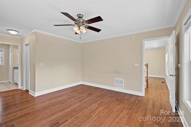 unfurnished room featuring light wood-style floors, baseboards, visible vents, and ornamental molding