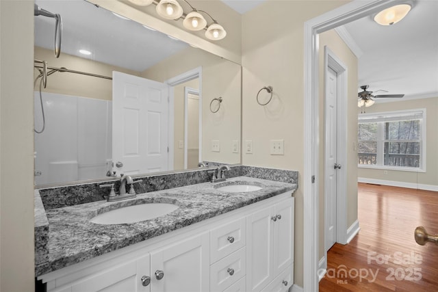 full bathroom featuring double vanity, a sink, baseboards, and wood finished floors