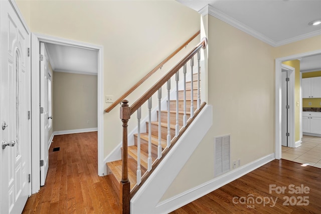 stairway featuring visible vents, wood finished floors, and ornamental molding