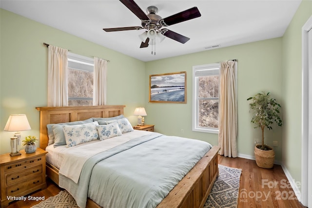 bedroom featuring a ceiling fan, baseboards, visible vents, and dark wood-type flooring