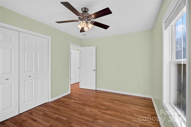 unfurnished bedroom with a closet, ceiling fan, baseboards, and wood finished floors