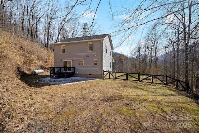 rear view of house with a deck, crawl space, fence, and a lawn