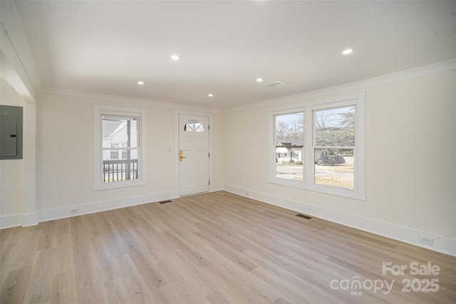 entrance foyer featuring ornamental molding, electric panel, and light wood-style flooring