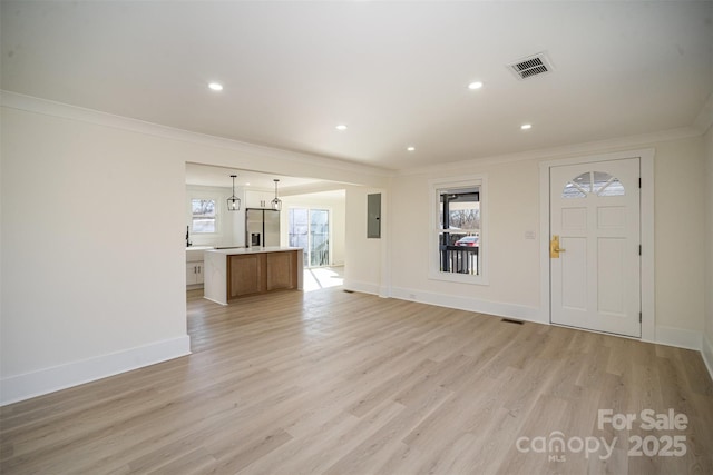 unfurnished living room with visible vents, light wood-style floors, baseboards, ornamental molding, and electric panel