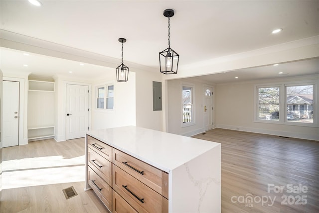 kitchen with light brown cabinets, visible vents, light wood-style floors, open floor plan, and hanging light fixtures