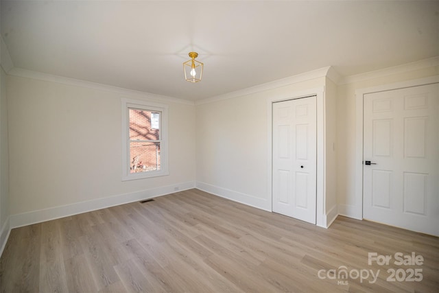 unfurnished bedroom featuring light wood finished floors, a closet, visible vents, ornamental molding, and baseboards