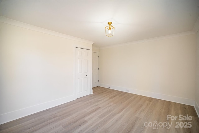 spare room featuring light wood-style flooring, baseboards, and crown molding