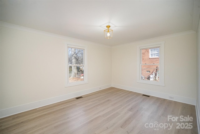 spare room featuring baseboards, light wood finished floors, and crown molding