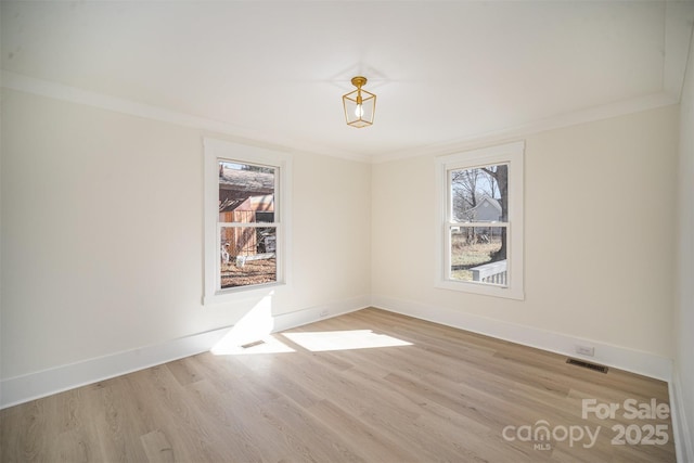 unfurnished room featuring light wood-style flooring, visible vents, baseboards, and crown molding