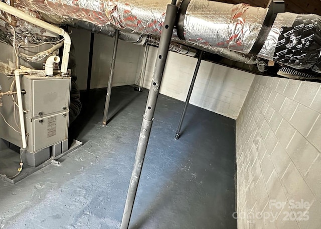 unfinished basement featuring concrete block wall and heating unit