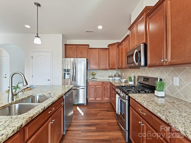 kitchen with pendant lighting, visible vents, appliances with stainless steel finishes, a sink, and light stone countertops