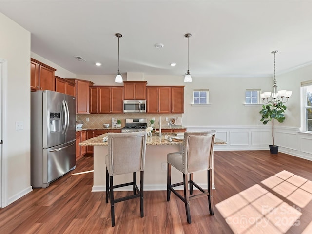 kitchen featuring hanging light fixtures, a kitchen island with sink, a breakfast bar area, and stainless steel appliances