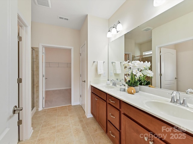 bathroom featuring visible vents, a walk in closet, and a sink