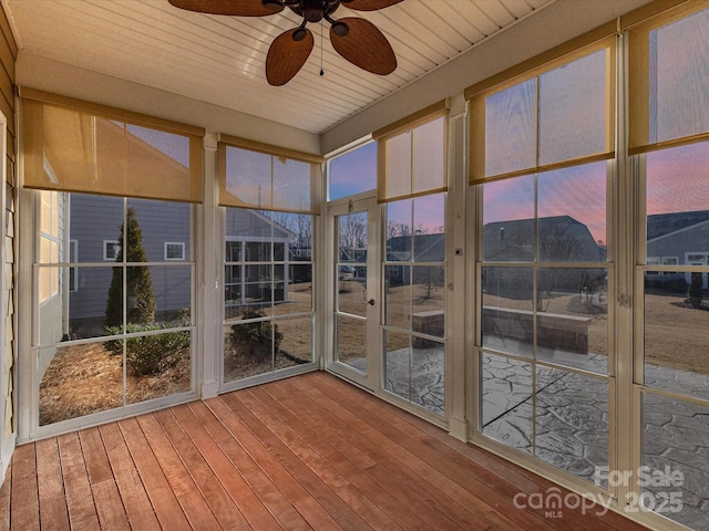 unfurnished sunroom featuring a healthy amount of sunlight, wooden ceiling, and a ceiling fan