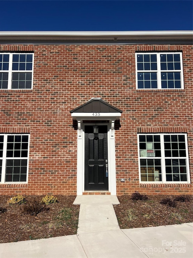 view of exterior entry featuring brick siding