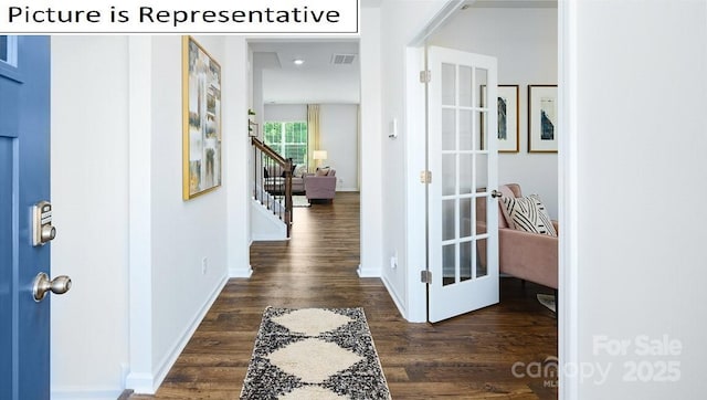 hallway with stairway, dark wood-style flooring, visible vents, and baseboards