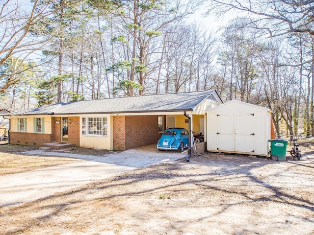 view of front of house with an outbuilding, brick siding, a storage shed, a carport, and driveway