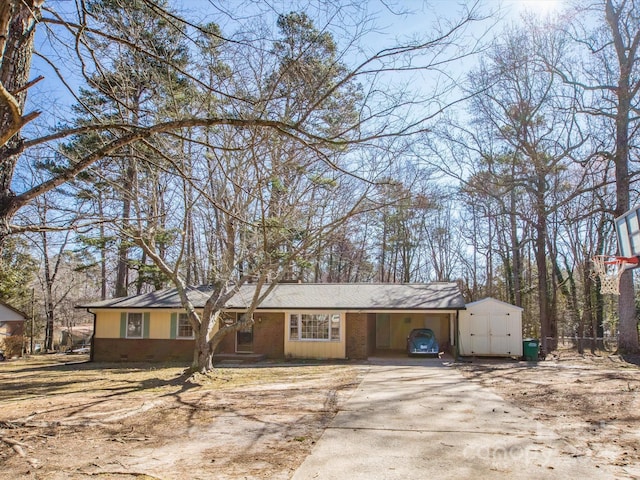 view of front of home featuring an outbuilding, concrete driveway, brick siding, and crawl space