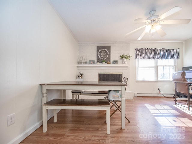 dining room with crown molding, a ceiling fan, baseboard heating, and wood finished floors