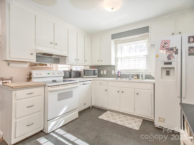 kitchen featuring under cabinet range hood, white appliances, a sink, light countertops, and decorative backsplash