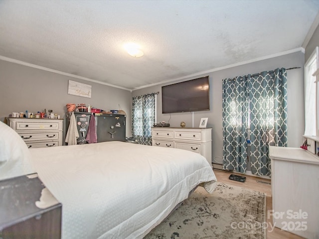 bedroom featuring light wood finished floors, ornamental molding, and a textured ceiling