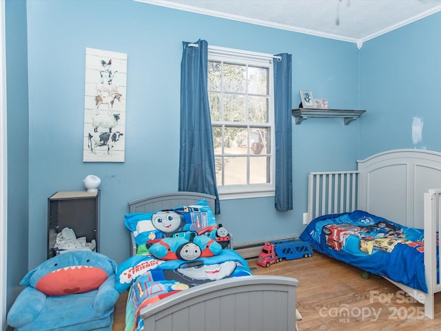 bedroom featuring crown molding, a baseboard heating unit, and wood finished floors