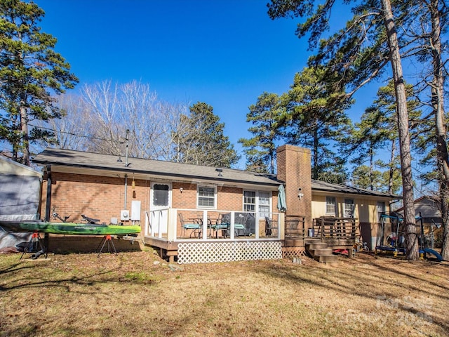 back of property with a deck, brick siding, a yard, and a chimney