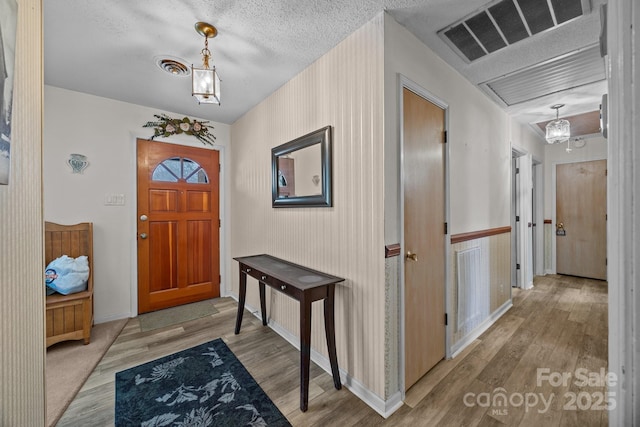 entryway with light wood-style floors, visible vents, and a textured ceiling