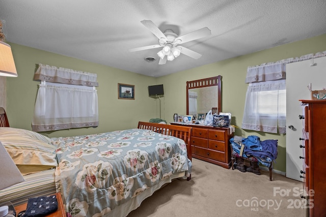 bedroom with a textured ceiling, ceiling fan, visible vents, and light colored carpet