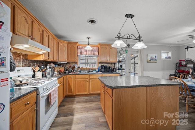 kitchen featuring white appliances, dark countertops, and decorative light fixtures