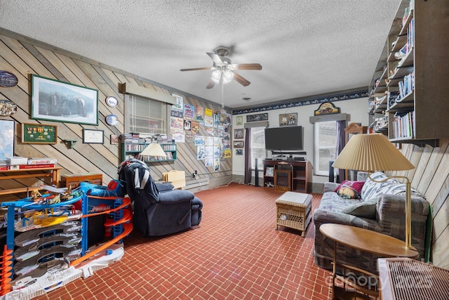 living room with brick floor, wooden walls, a textured ceiling, and a ceiling fan