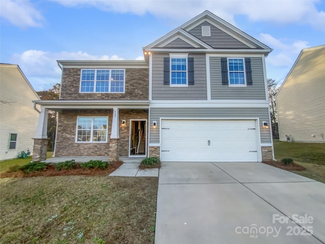 craftsman-style house with stone siding, a front lawn, an attached garage, and driveway