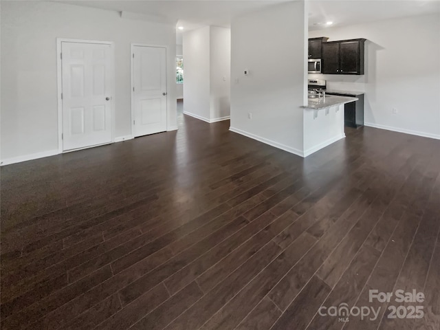 unfurnished living room with recessed lighting, dark wood-style flooring, and baseboards