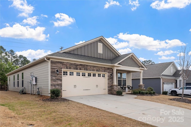 view of front of house with board and batten siding, stone siding, an attached garage, and concrete driveway