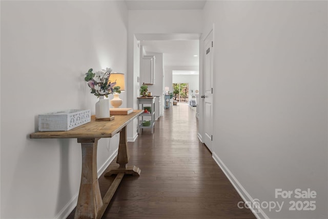 hall featuring baseboards and dark wood-type flooring