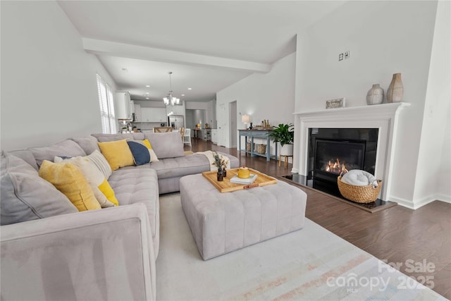 living room featuring a chandelier, wood finished floors, baseboards, beam ceiling, and a glass covered fireplace