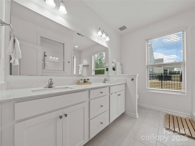 full bath with a tile shower, a sink, visible vents, and a healthy amount of sunlight