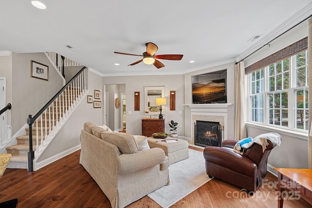 living area with visible vents, crown molding, stairway, and wood finished floors