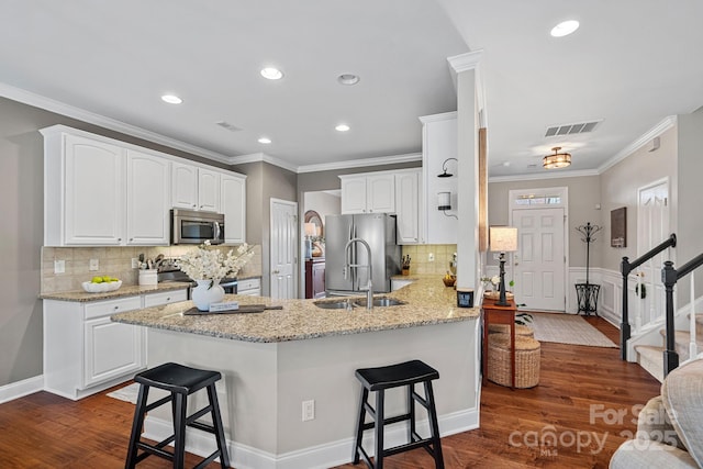 kitchen with stainless steel appliances, a peninsula, visible vents, a kitchen breakfast bar, and dark wood-style floors